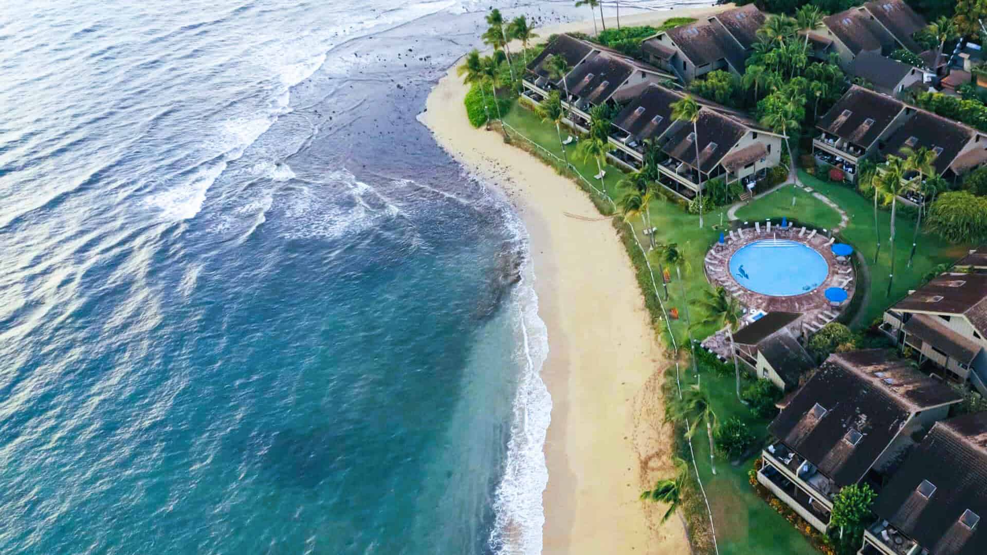 Aerial view of Kahana Village resort, highlighting its beachfront and lush greenery.