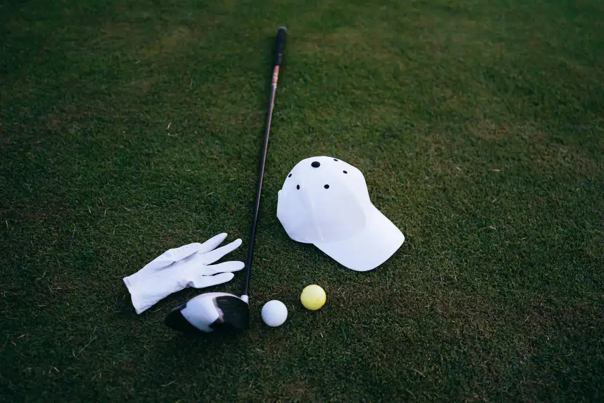 A white golf hat, gloves, and a golf ball resting on green grass at Maui Golf Courses near Kahana Village.