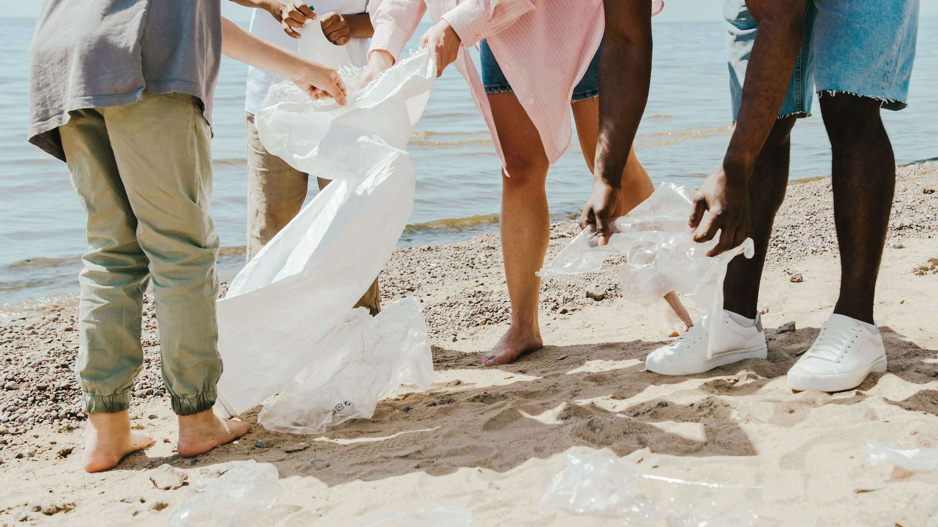 Volunteers collecting plastic bags on a Maui beach cleanup.