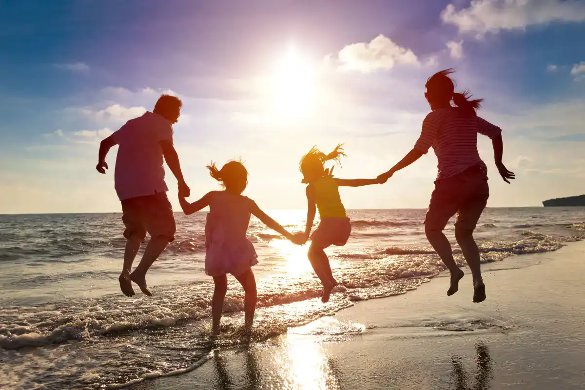 Happy family jumping on the beach at sunset at Kahana Village.