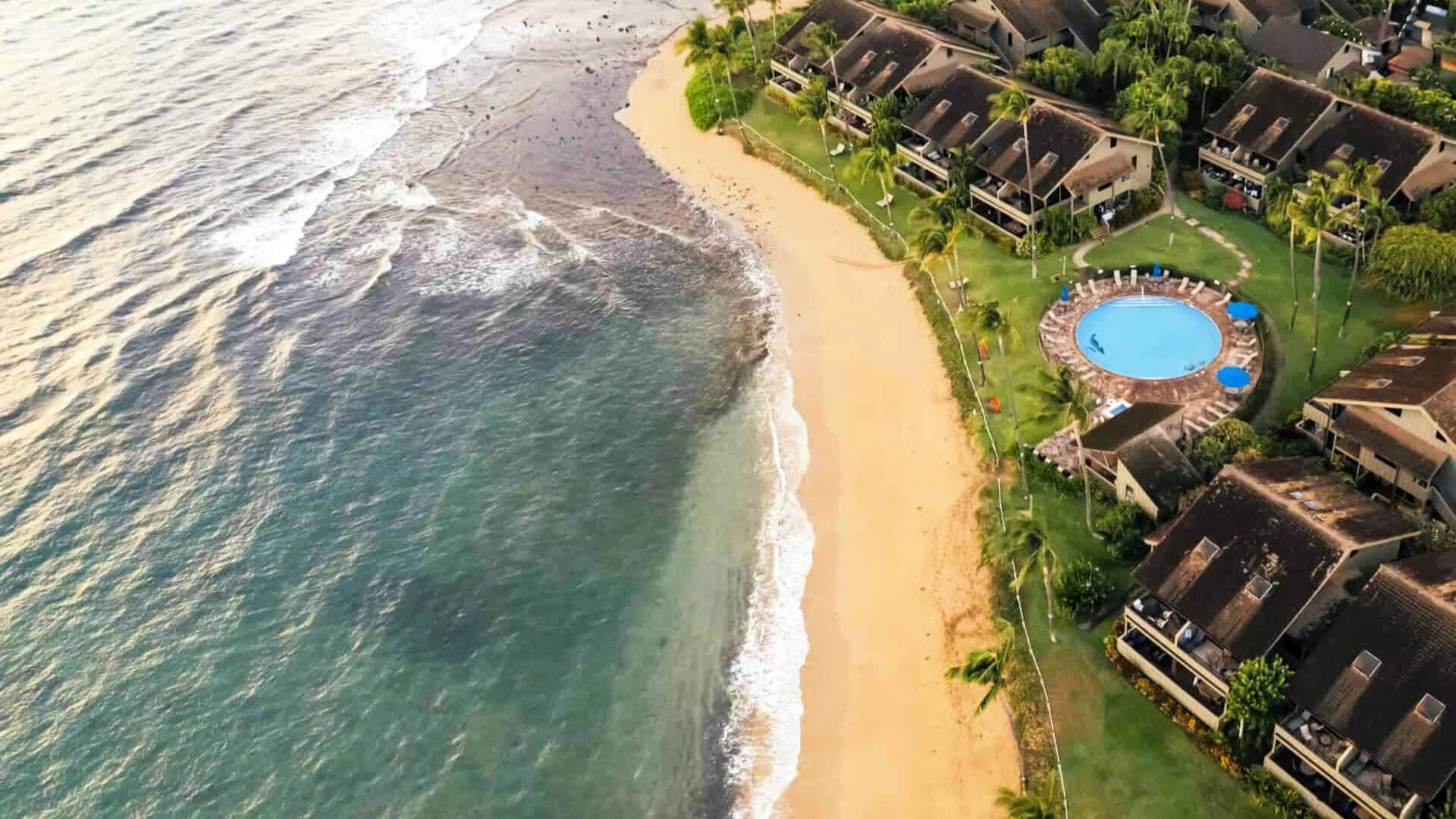 Aerial view of Kahana Village beach resort, highlighting its beachfront and lush greenery.
