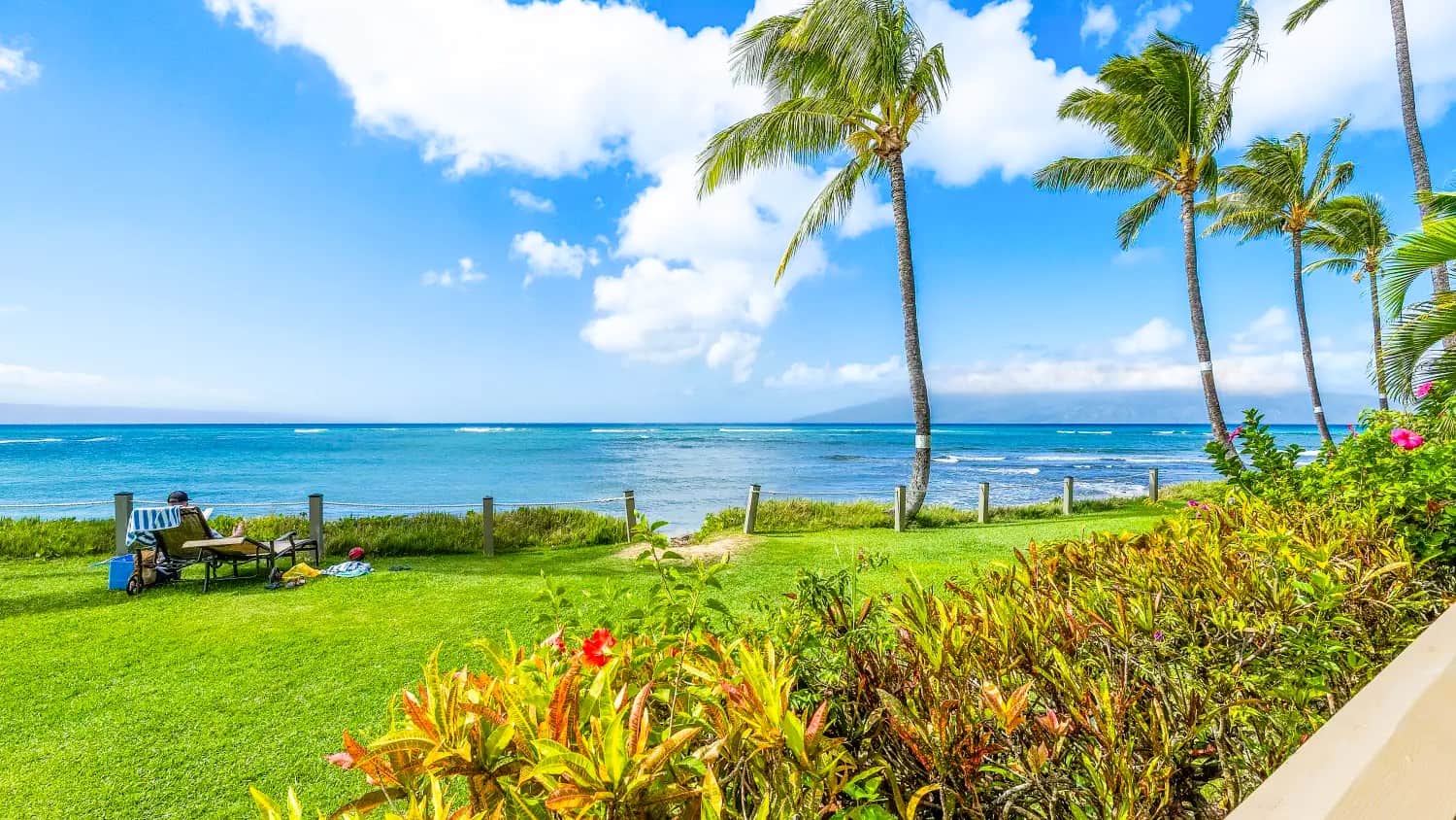 Ocean view from Kahana Village condo balcony, featuring serene beachfront and clear waters.
