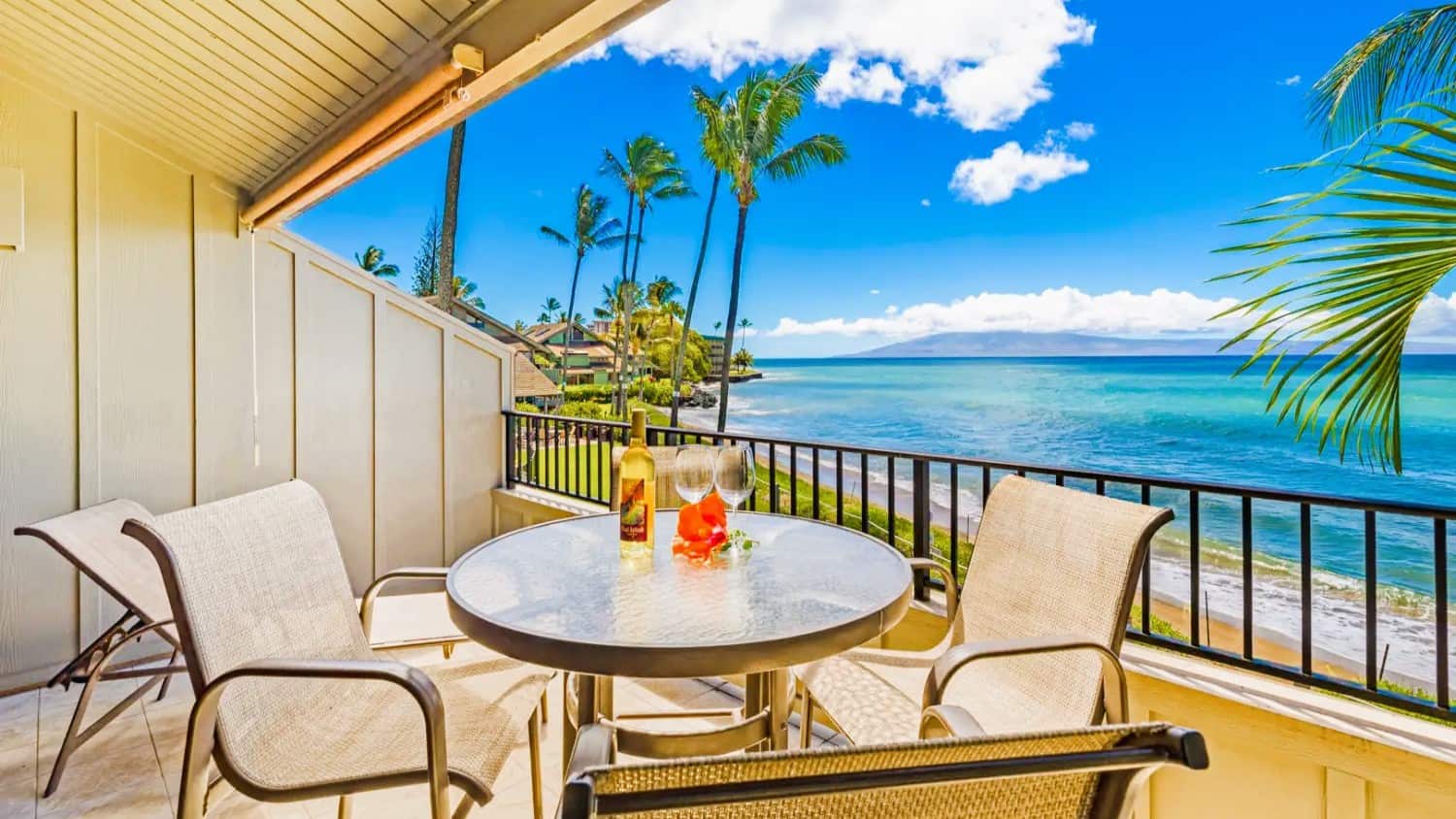 Kahana Village balcony featuring chairs and a table, overlooking the serene ocean.  