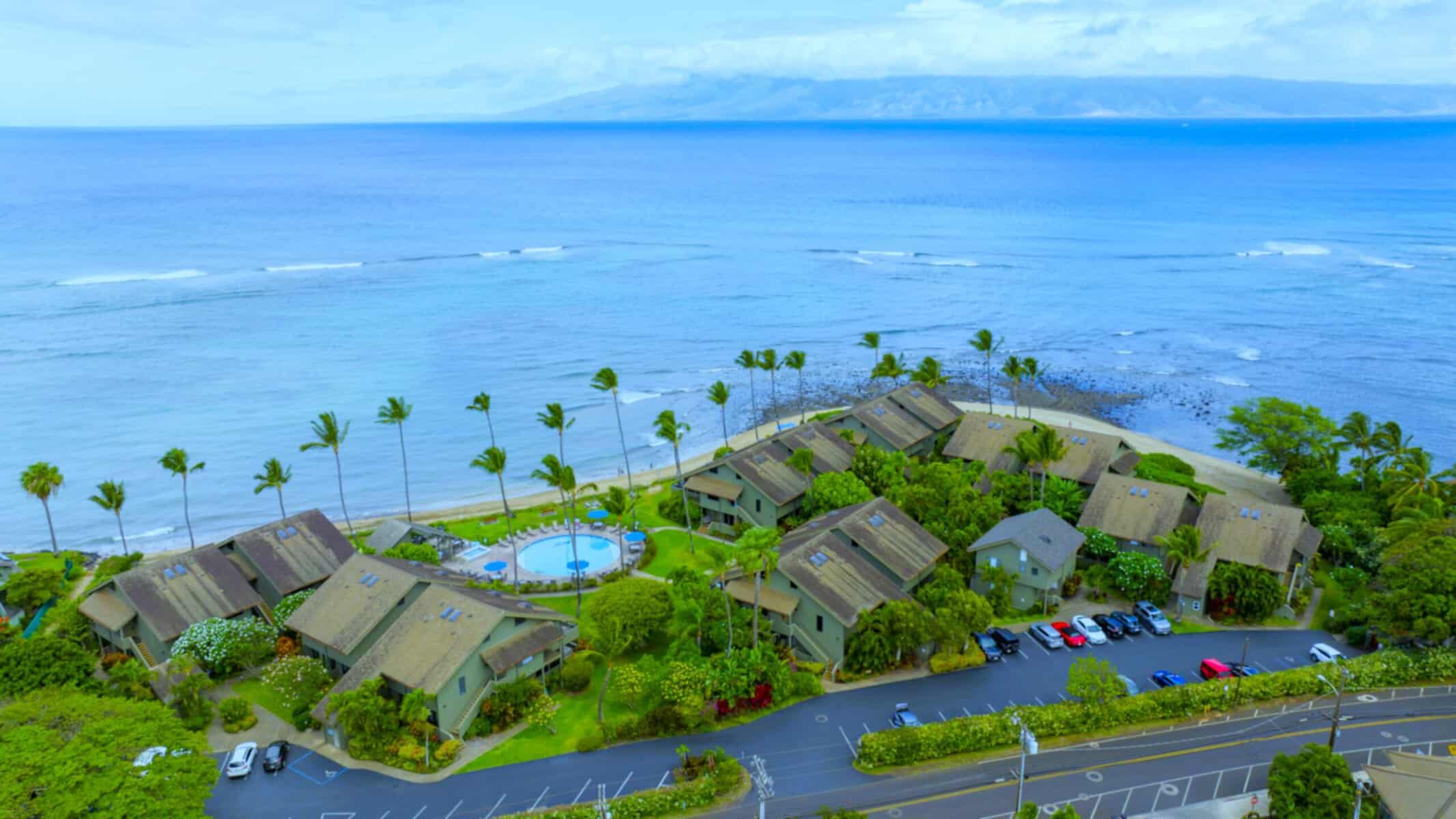 Stunning aerial view of Kahana Village, highlighting the turquoise ocean and the inviting beach resort below.  