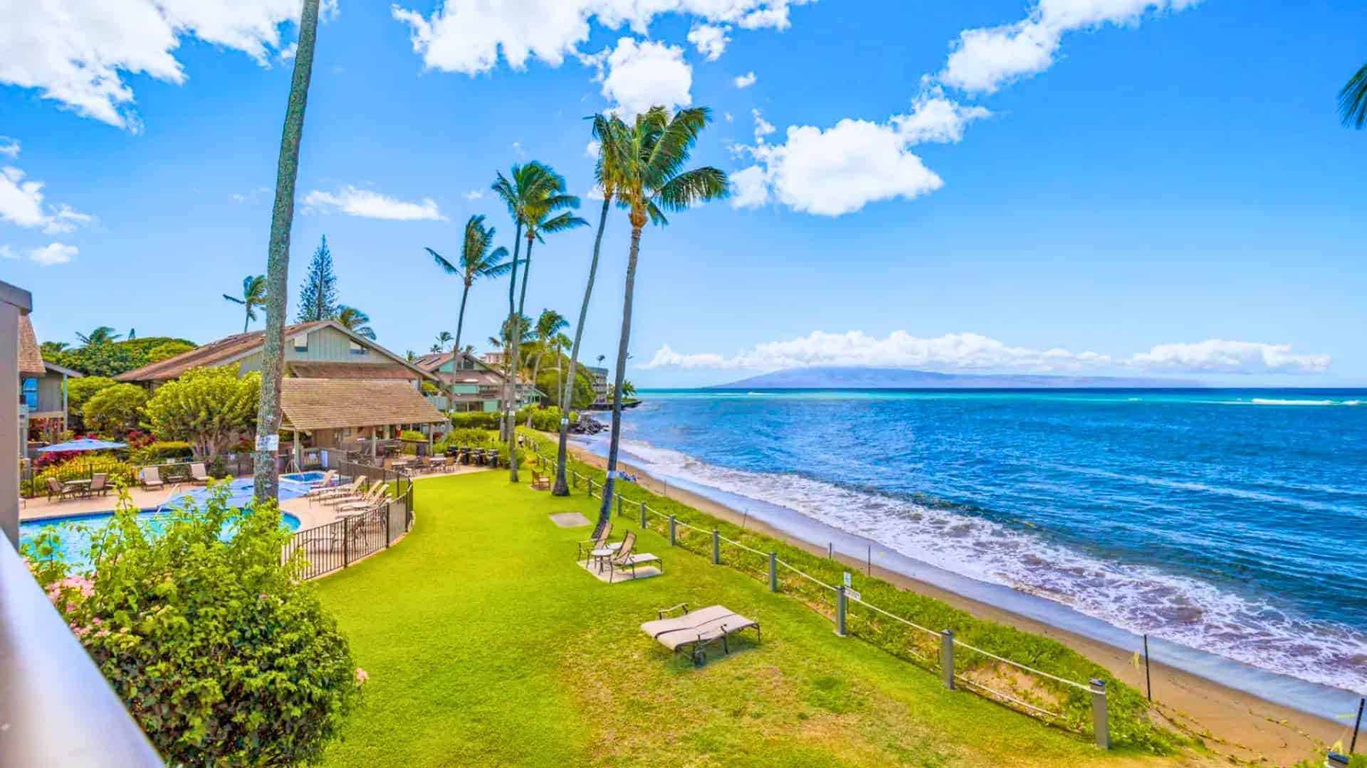 Scenic view from a Kahana Village balcony, highlighting the tranquil beach and ocean horizon.